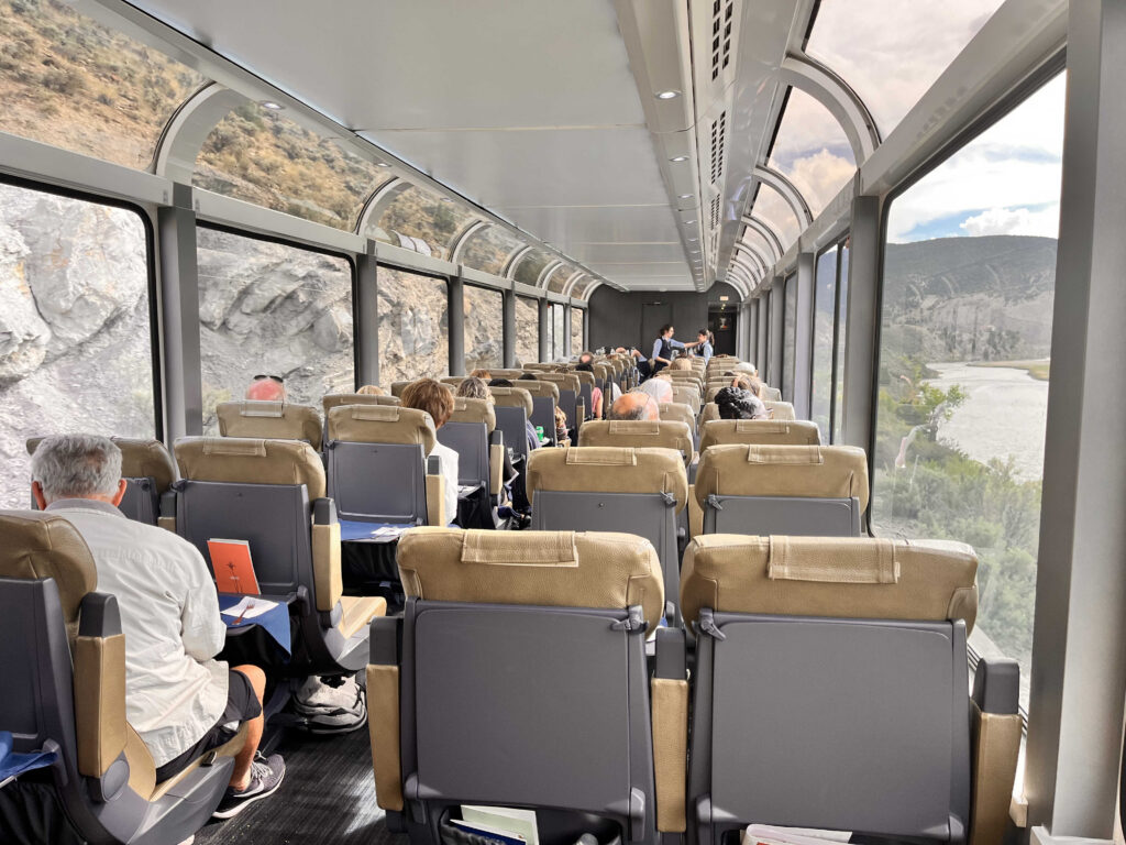 Photo from inside a glass-domed train showing rows of seats.