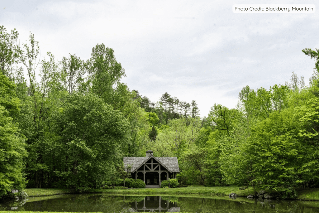 A charming wooden pavilion reflected in a calm pond, nestled among vibrant green trees and lush forest at Blackberry Mountain in Tennessee’s Great Smoky Mountains.