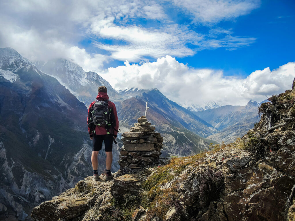 a man standing atop a mountain next to some cairns